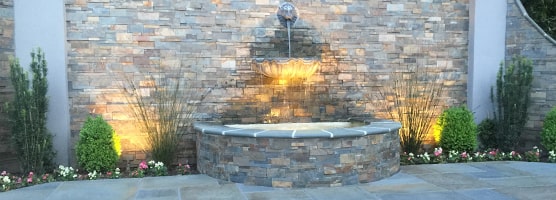 water fountain with lighting effect in front of a brick fence